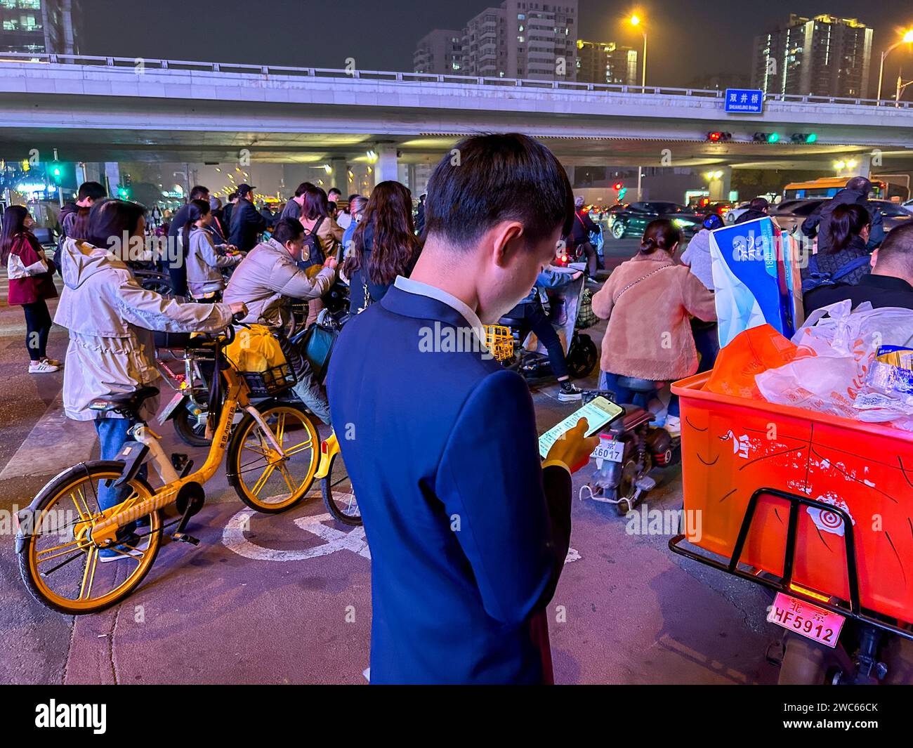 Pekín, China, gente grande de la multitud, esperando a cruzar la calle en la noche, escena de la calle, hombre mirando el teléfono inteligente Foto de stock