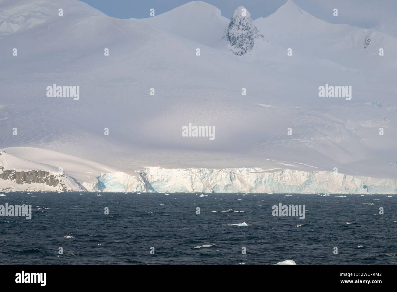 Brialmont Cove, antártida En un día nublado en primavera, hielo y la costa cubierta de nieve con arcos de hielo y cuevas nubes de la antártida claro, cielo azul Foto de stock