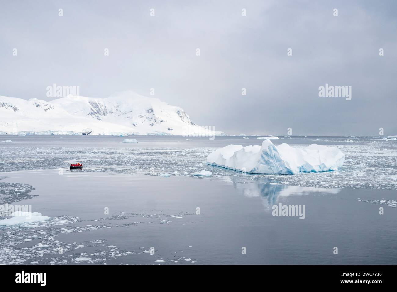 Zodiaco navegando a través del hielo en Neko Harbor, Antártida, agua llena de hielo y icebergs en su lugar, reflejos y picos nevados Foto de stock