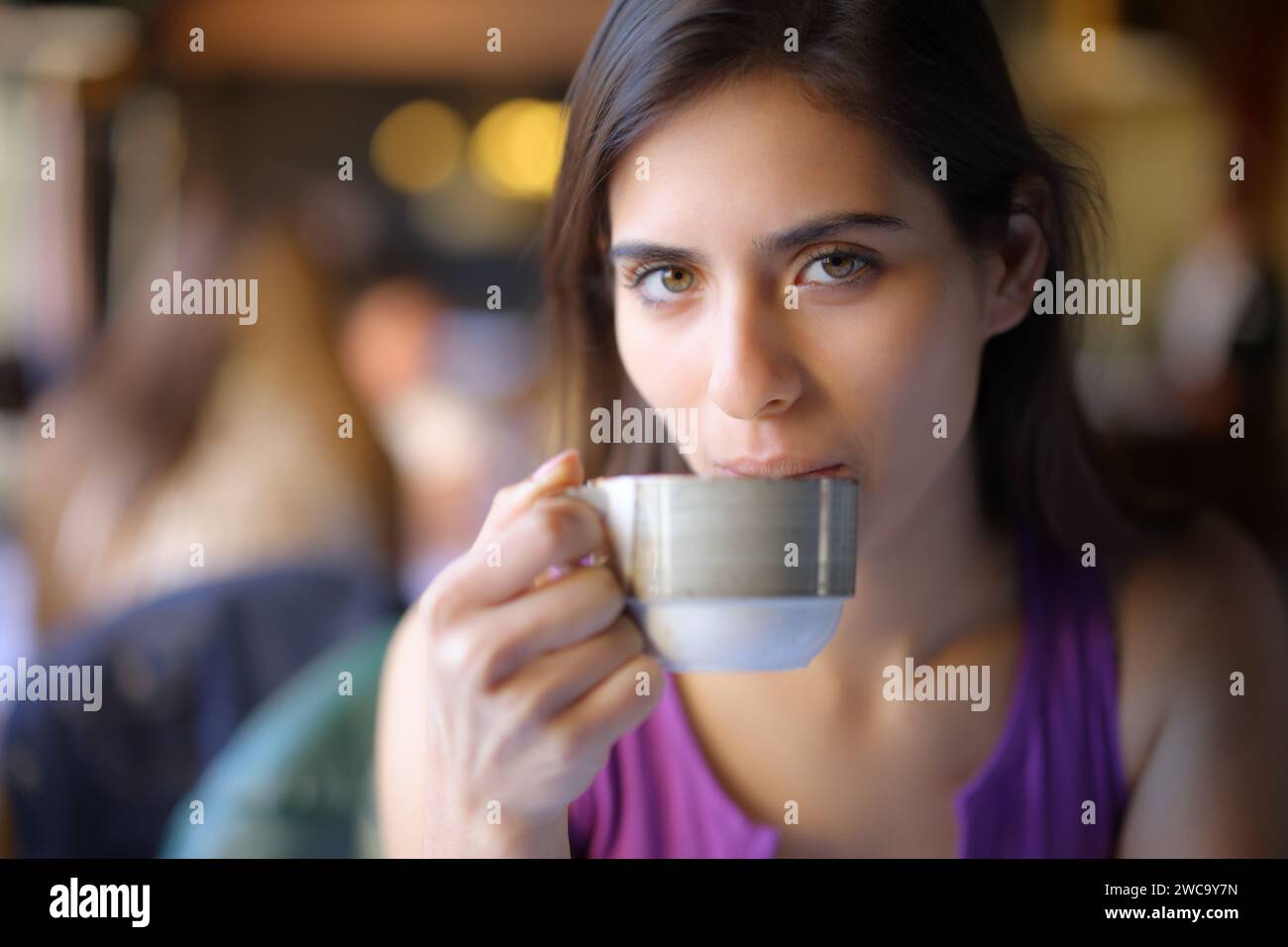 Hermosa mujer bebiendo café mirándote en una tienda Foto de stock