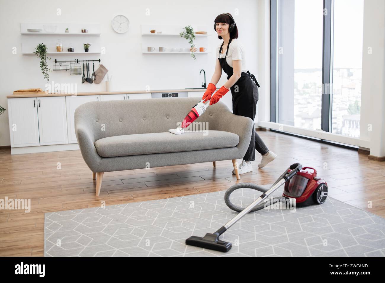 El limpiador del servicio de limpieza doméstica está eliminando la suciedad  y el polvo del sofá usando una máquina de extracción de limpieza en seco  línea en el sofá después de la