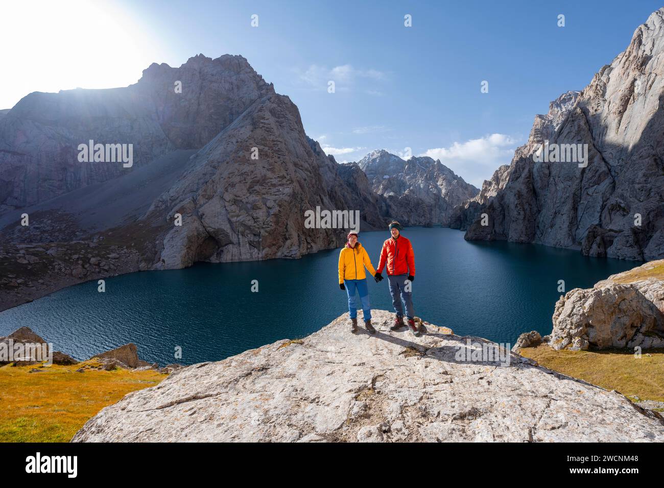 Pareja en el lago de montaña azul entre picos rocosos empinados de las montañas, el lago Kol Suu, las montañas de Sary Beles, la provincia de Naryn, Kirguistán Foto de stock