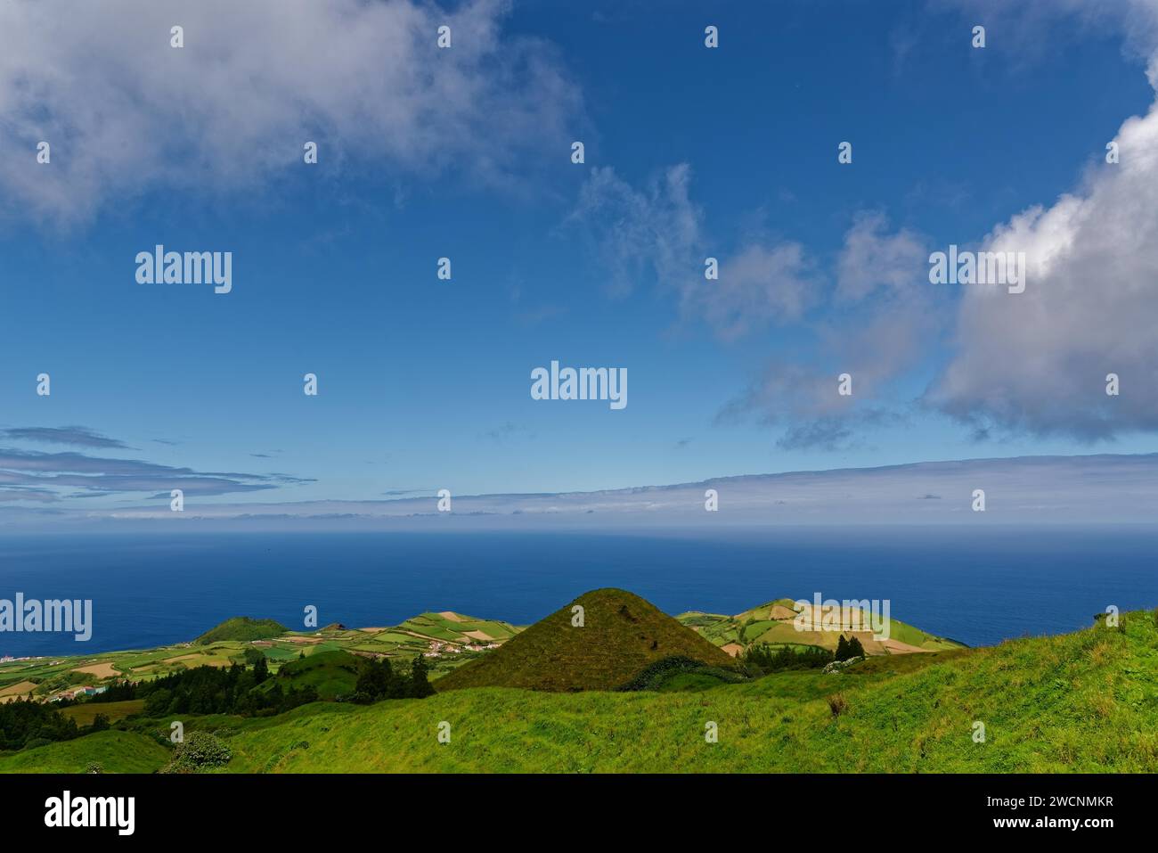 Vistas panorámicas sobre verdes colinas volcánicas que se desvanecen suavemente en el mar bajo un gran cielo, Caldeira das Sete Cidades, Sete Cidades, Isla Sao Miguel Foto de stock