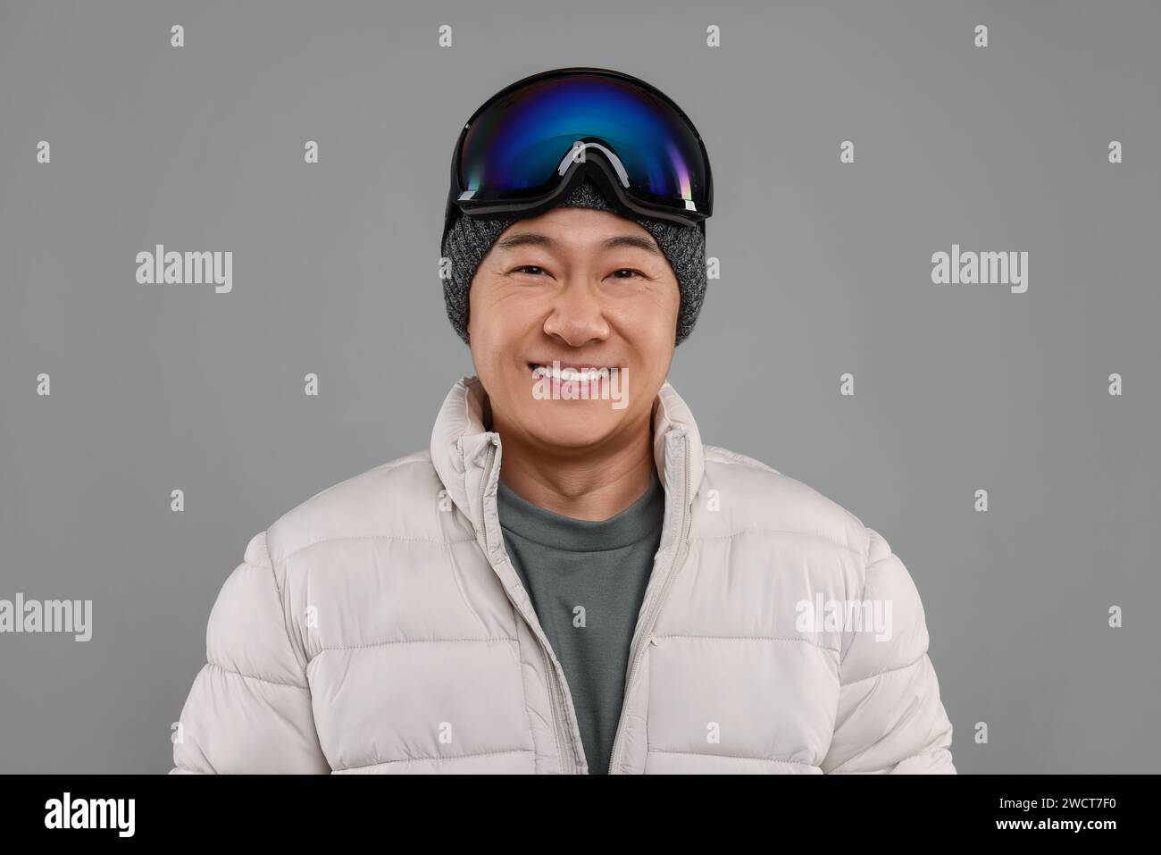 Deportes de invierno. Hombre feliz con gafas de esquí sobre fondo gris Foto de stock