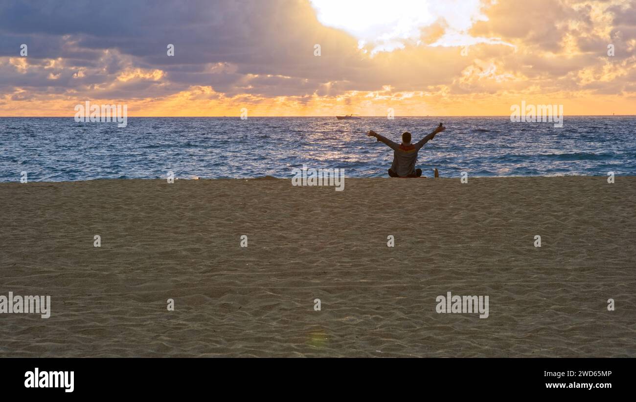 Un amante del amanecer saludando la primera luz sobre el horizonte oriental en la playa sur Foto de stock
