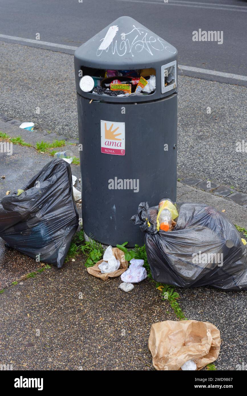 Cubo de residuos y bolsas de plástico llenas de basura. Ama (Empresa Municipal de Medio Ambiente) en EUR, Roma, Italia Foto de stock