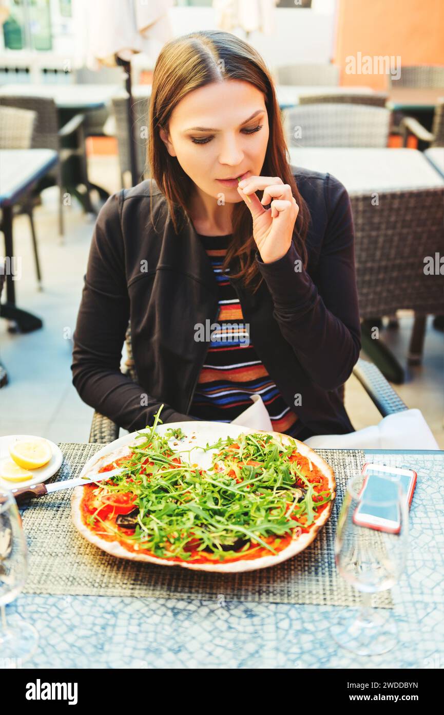 Mujer joven en forma comiendo pizza vegetariana en el restaurante Foto de stock