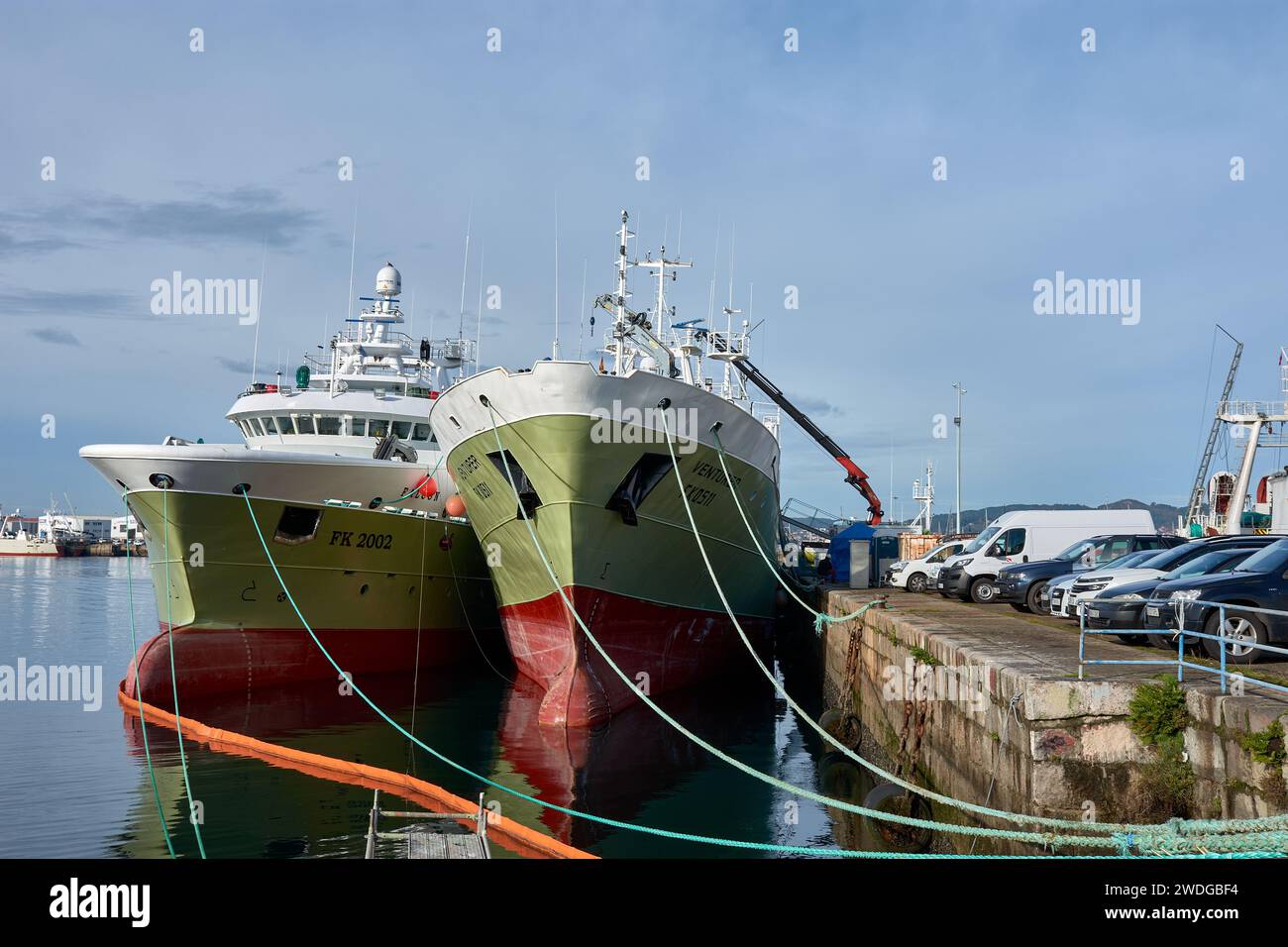 VIGO, ESPAÑA-DICIEMBRE,19,2021: Barcos pesqueros verdes atracados con cuerdas en el puerto de Vigo cargando material para volver al mar Foto de stock