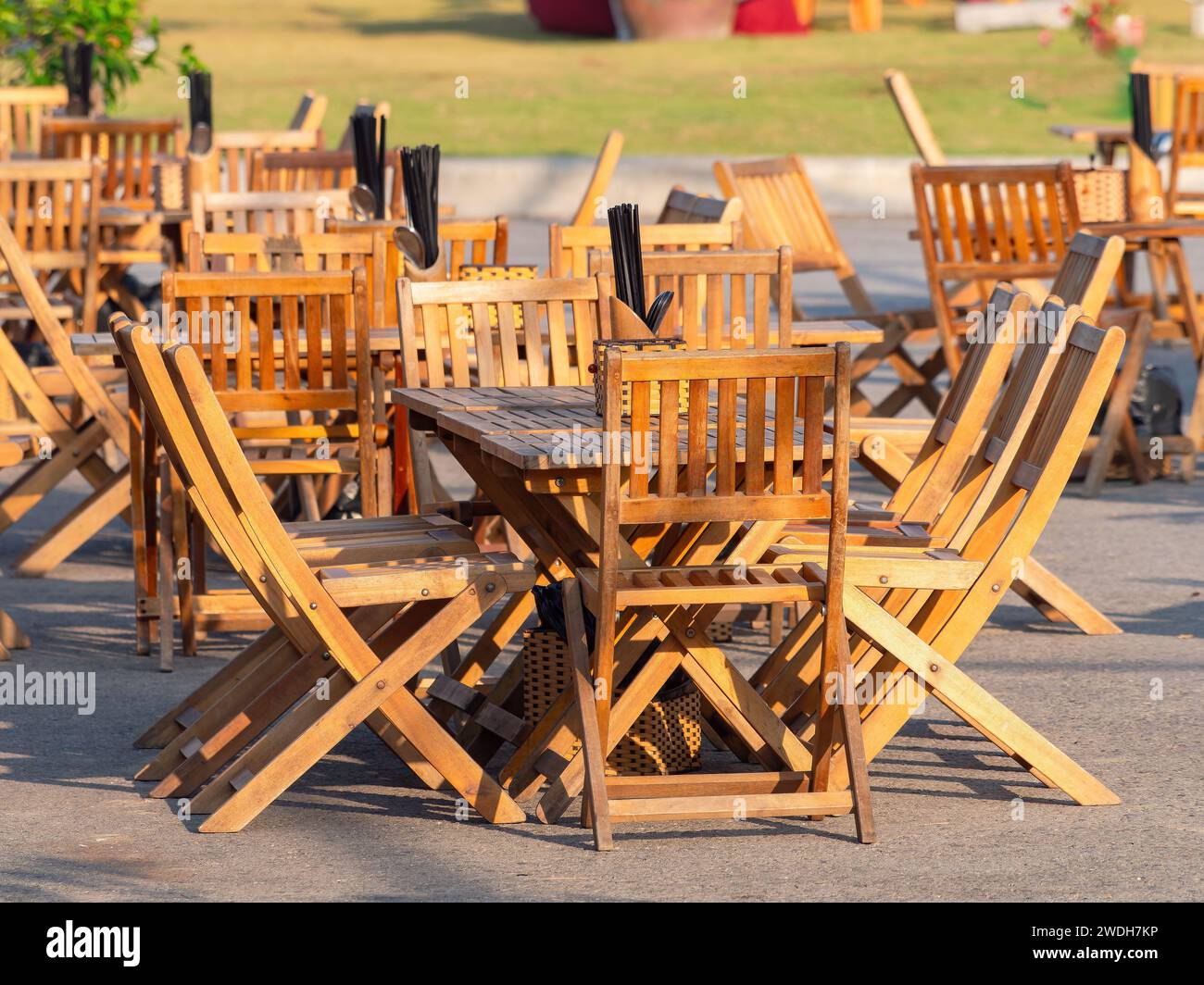 Muebles de teca en un restaurante vacío al aire libre en un resort de verano en Asia. Chop negro palos en cada mesa. Foto de stock