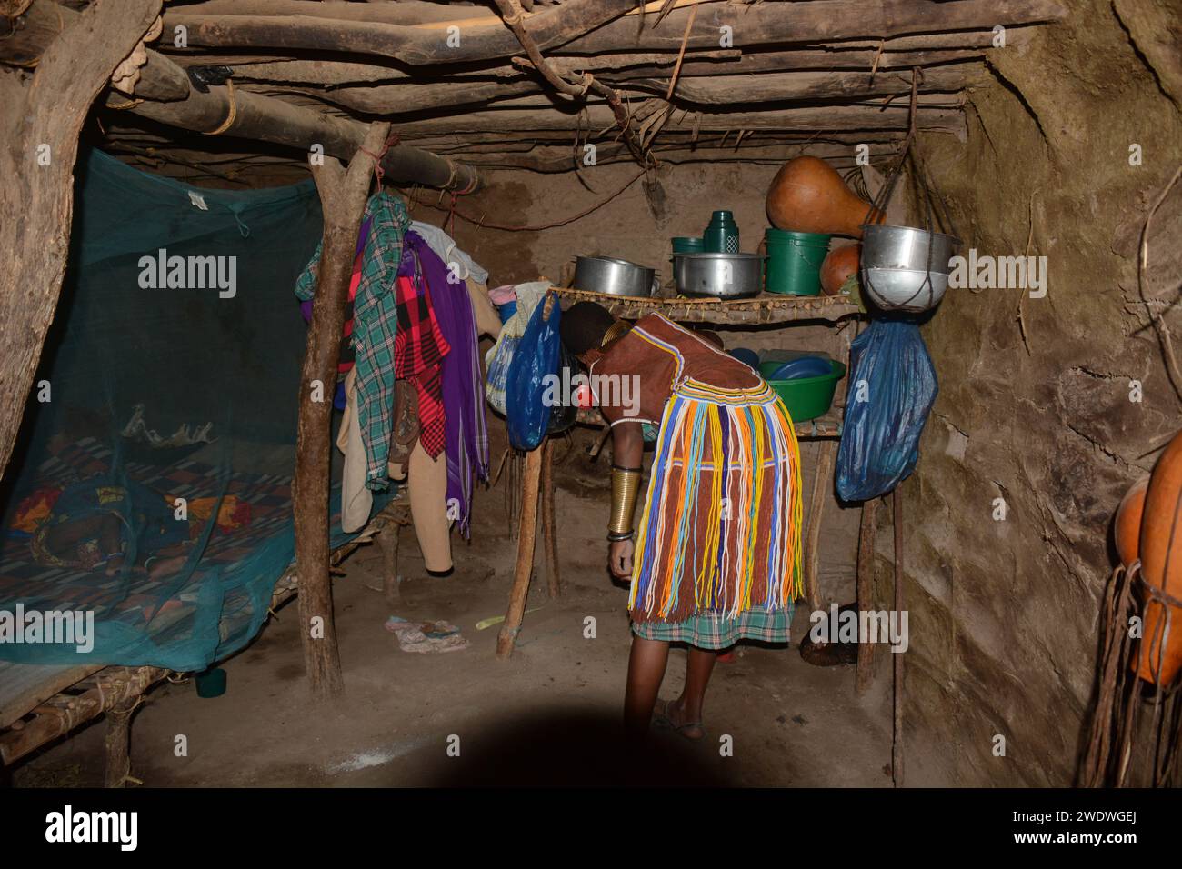 Mujer Datoga en el tradicional vestido de cuero adornado con abalorios y pulseras de latón moler el grano en harina. Foto de stock