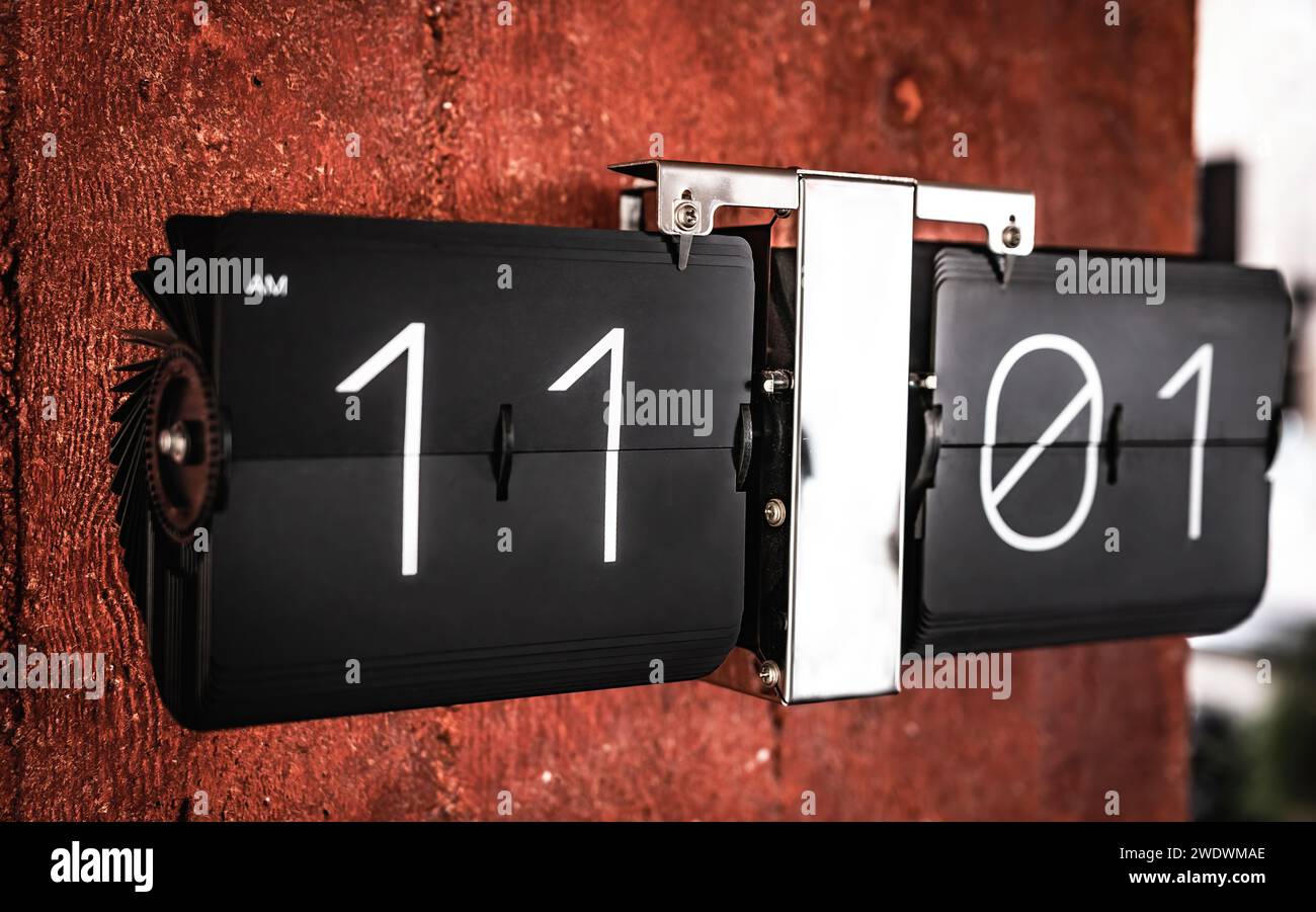 Flip reloj negro con once en punto de la hora en el panel de primer plano. Reloj con números de horas y minutos Foto de stock