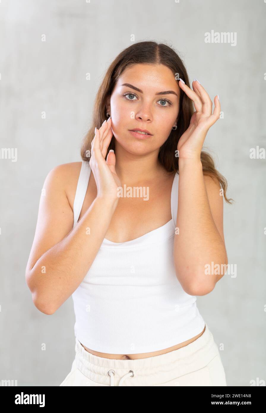 Mujer joven en ropa casual que cuida de su piel Foto de stock