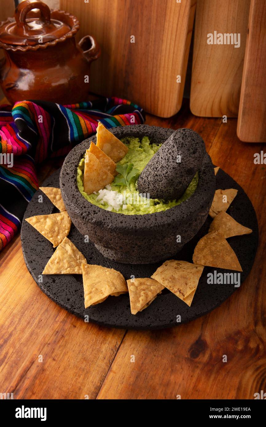 Molcajete mexicano de piedra volcánica relleno de guacamole con salsa de  queso chips de maíz y salsa picante con pico de gallo