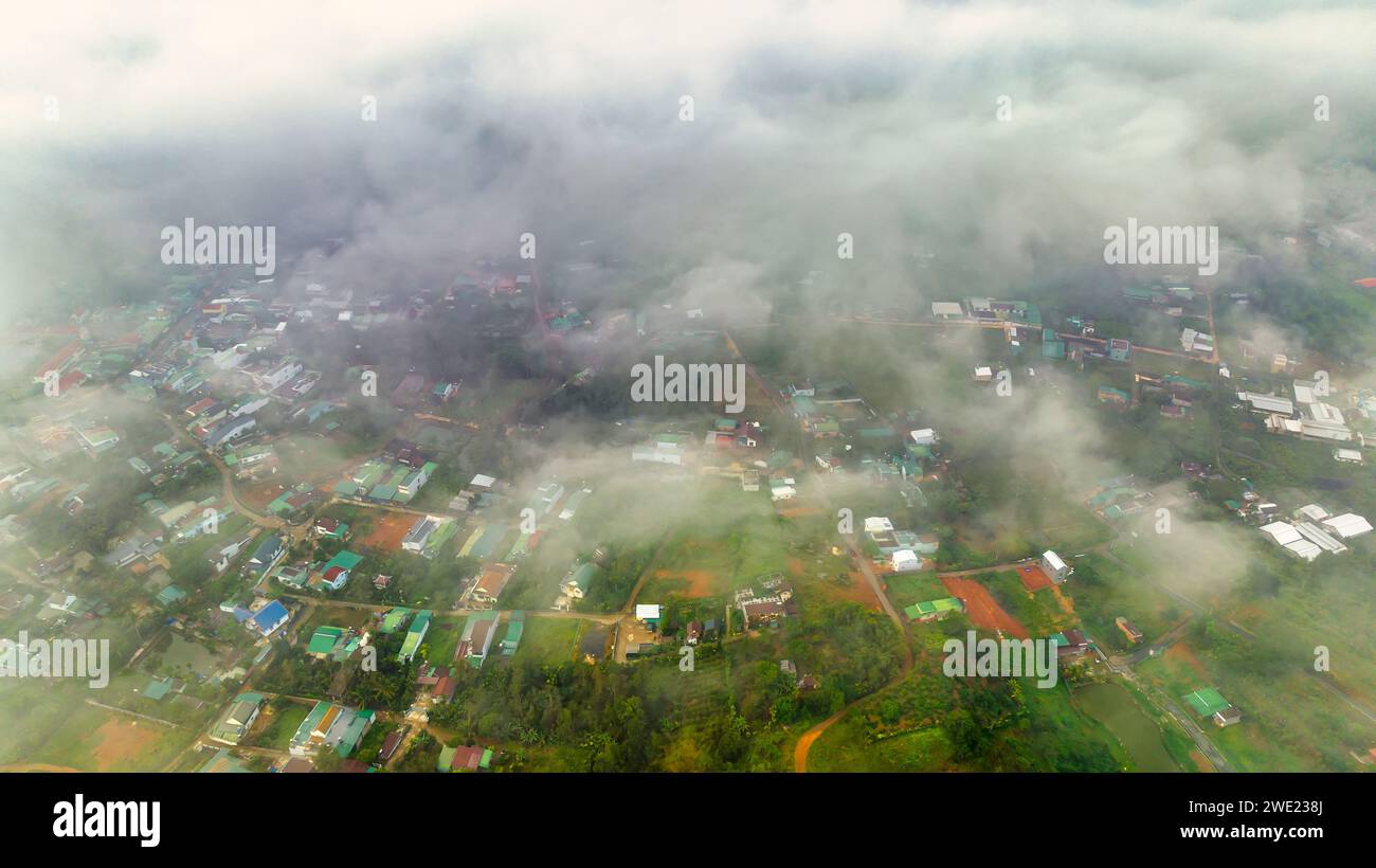Vista aérea del paisaje urbano de Bao Loc por la mañana con cielo brumoso en las tierras altas de Vietnam. Textura de desarrollo urbano, infraestructura de transporte y parques verdes Foto de stock