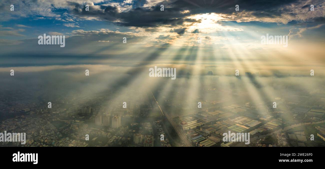 Vista aérea del paisaje urbano de Saigón por la mañana con rayos de sol brumosos en el sur de Vietnam. Textura de desarrollo urbano, infraestructura de transporte y verde Foto de stock