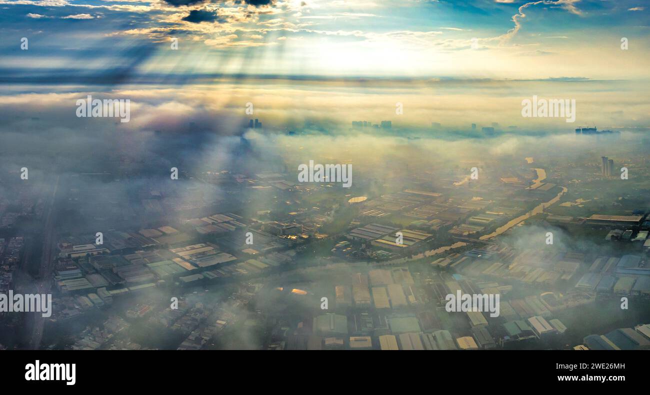 Vista aérea del paisaje urbano de Saigón por la mañana con rayos de sol brumosos en el sur de Vietnam. Textura de desarrollo urbano, infraestructura de transporte y verde Foto de stock