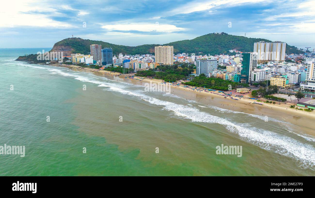 Vista aérea de la ciudad de Vung Tau con hermosa puesta de sol y tantos barcos. Vista panorámica costera de Vung Tau desde arriba, con olas, costa, calles Foto de stock