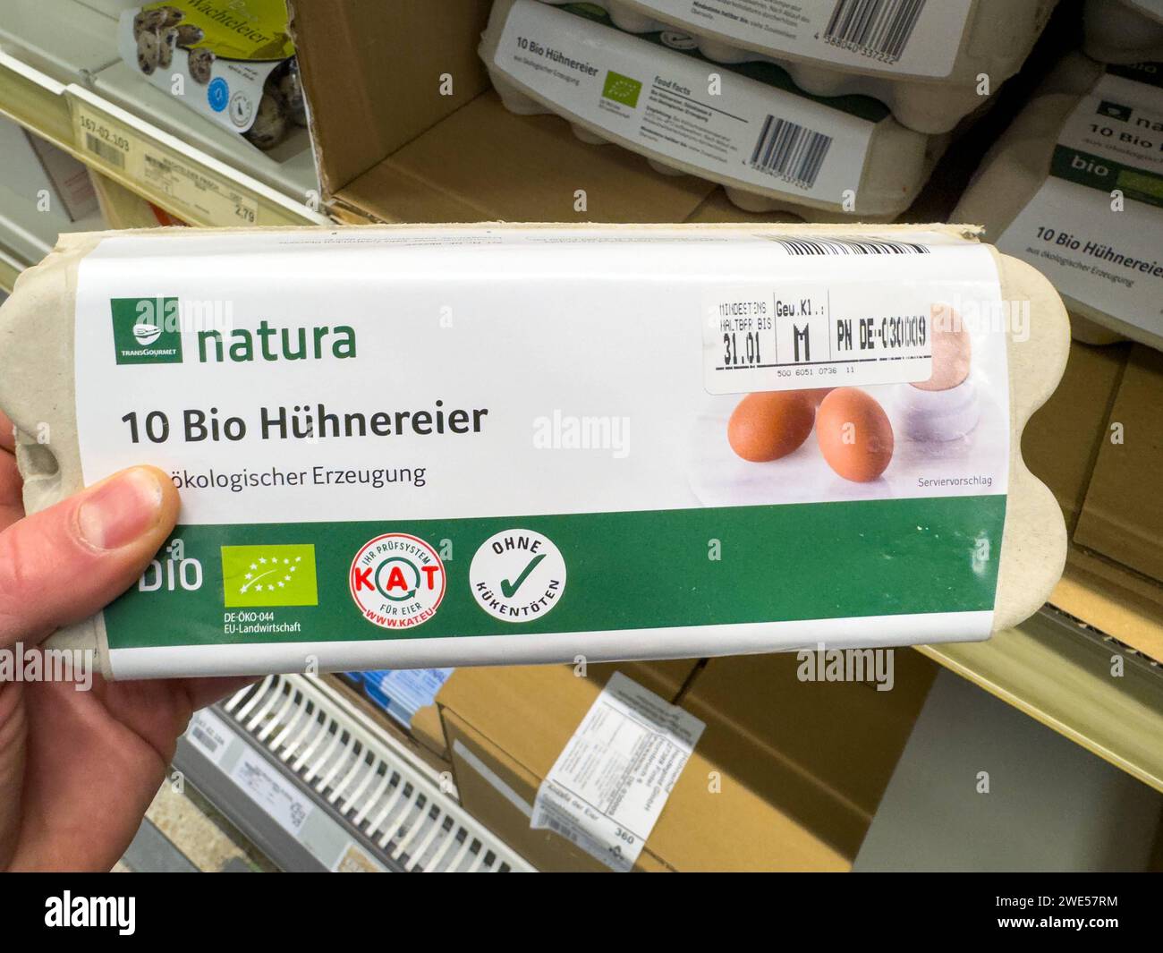 Baviera, ALEMANIA - 13 de enero de 2024: Un hombre sostiene una caja de huevos orgánicos en un supermercado *** Ein Mann hält eine Packung Bio Eier in einem Supermarkt Foto de stock