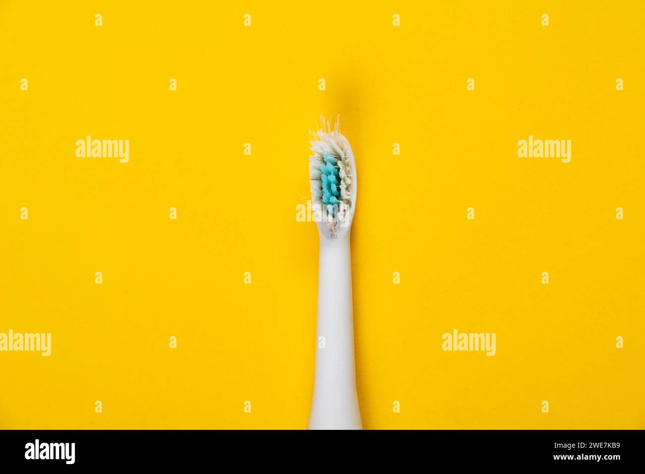 Cabezal de cepillo usado de un cepillo de dientes eléctrico delante de un fondo monocromo Foto de stock