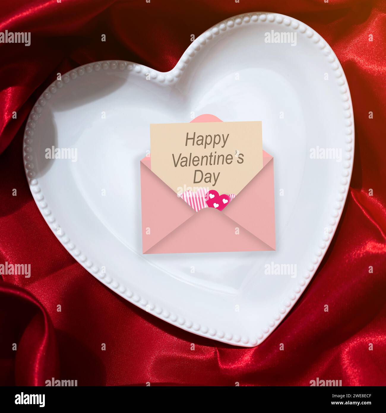 Placa de corazón con letras de San Valentín sobre un fondo de servilleta roja. Cena romántica Concepto del Día de San Valentín Foto de stock
