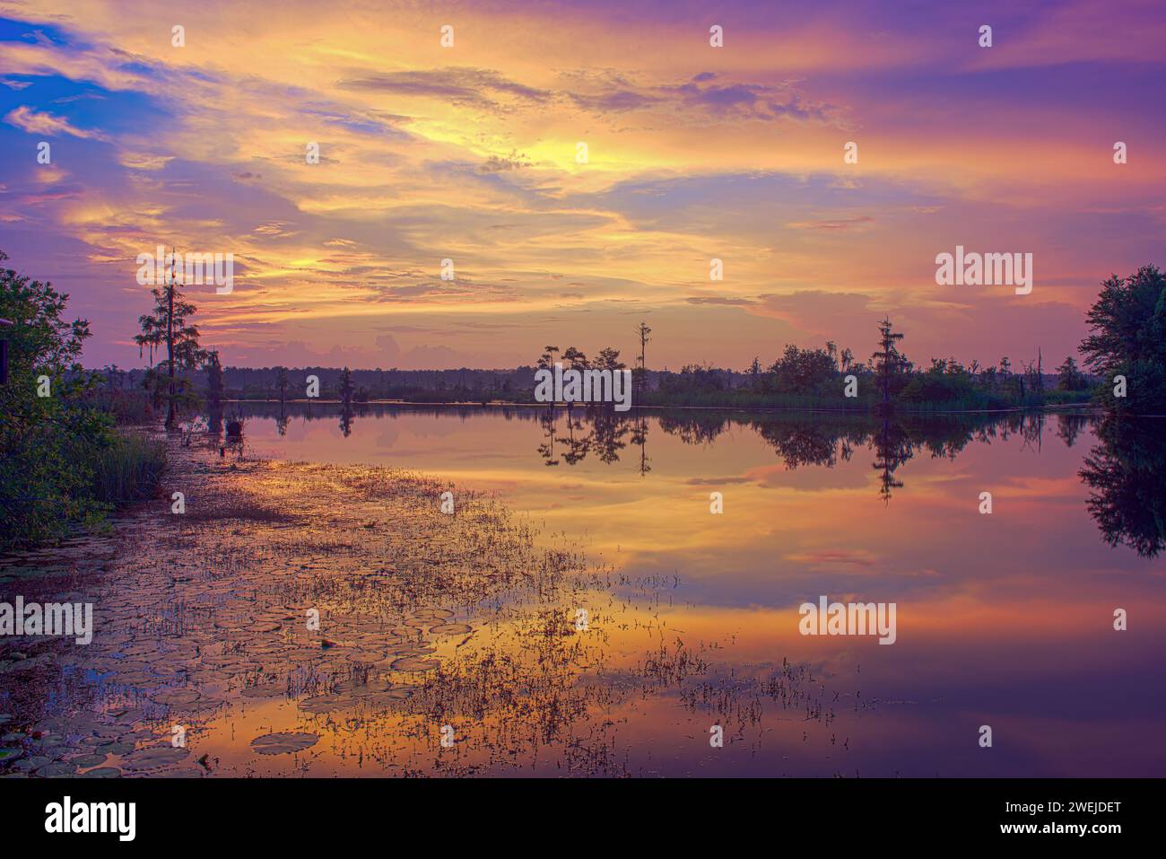 A medida que el día se retira suavemente a la noche, el cielo se convierte en un lienzo de tonos vibrantes, proyectando una paleta encantadora reflejada en las aguas serenas. Foto de stock