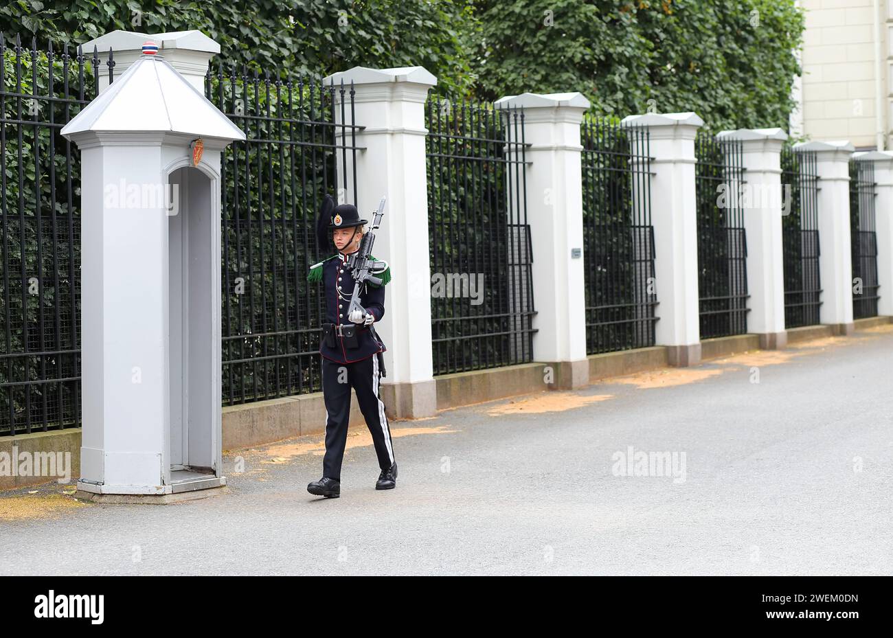 Oslo, Noruega -18 de agosto de 2023: La joven mujer en uniforme especial de la Guardia Real, tropas domésticas de pie en centinela con arma de fuego junto a la Roya Foto de stock