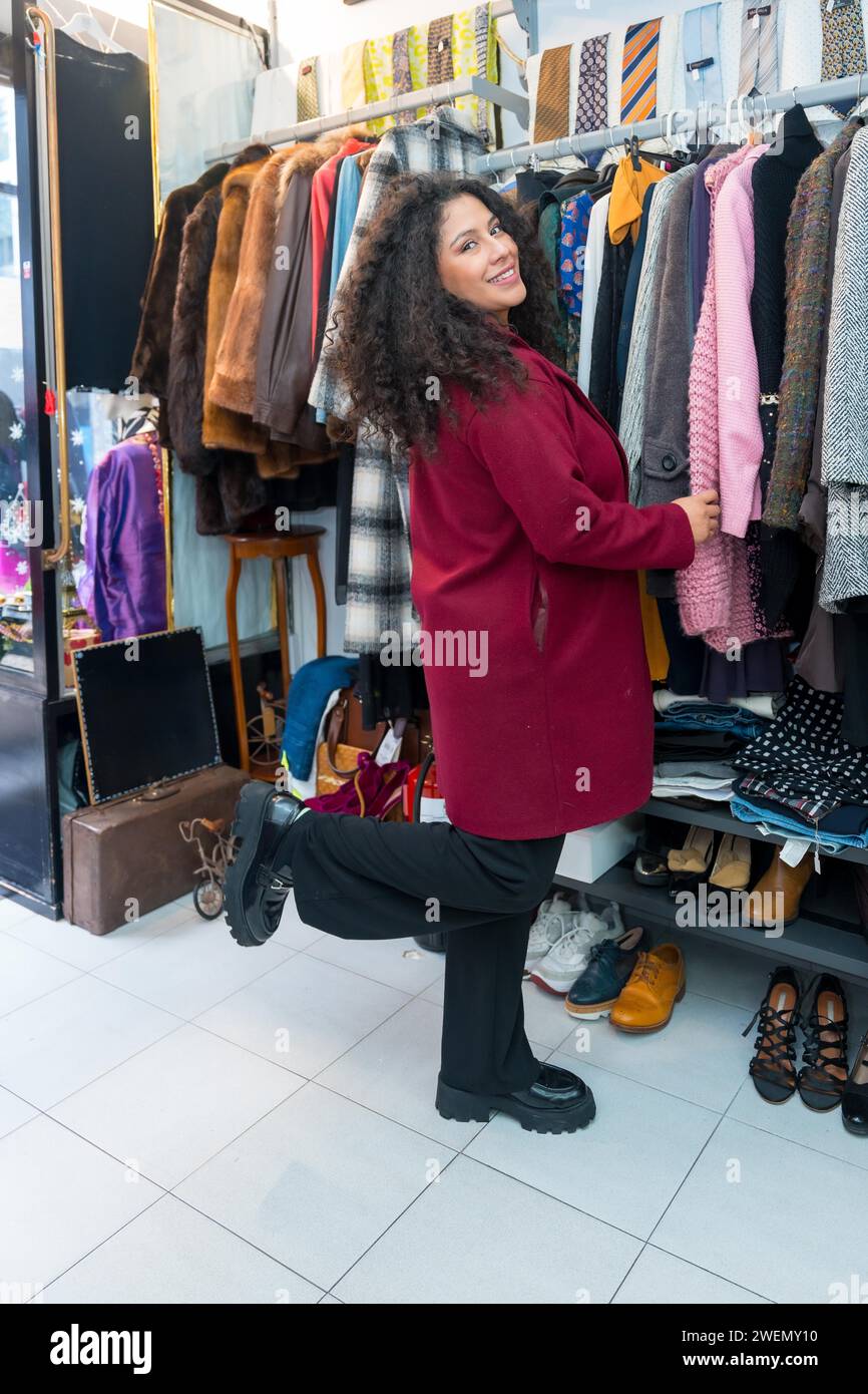 Foto vertical de una mujer feliz de compras en una tienda vintage durante las ventas Foto de stock
