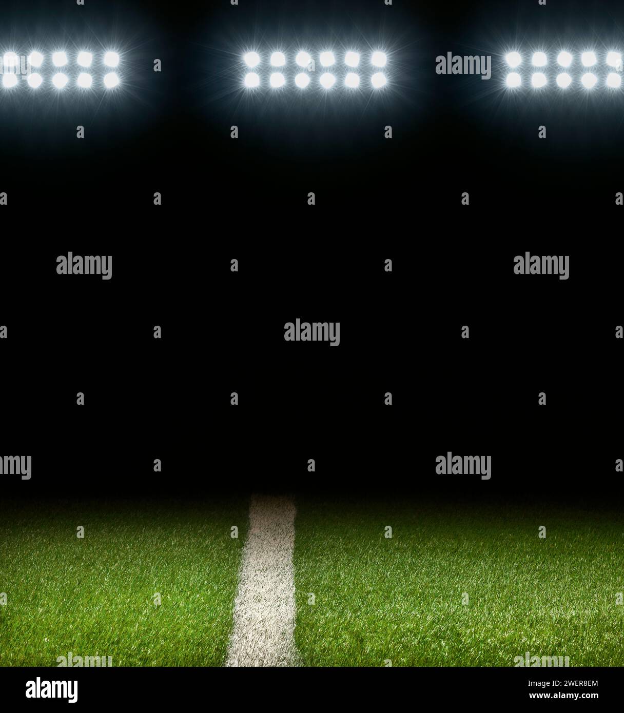 Campo atlético de hierba con raya blanca y fondo oscuro debajo de las luces del estadio Foto de stock