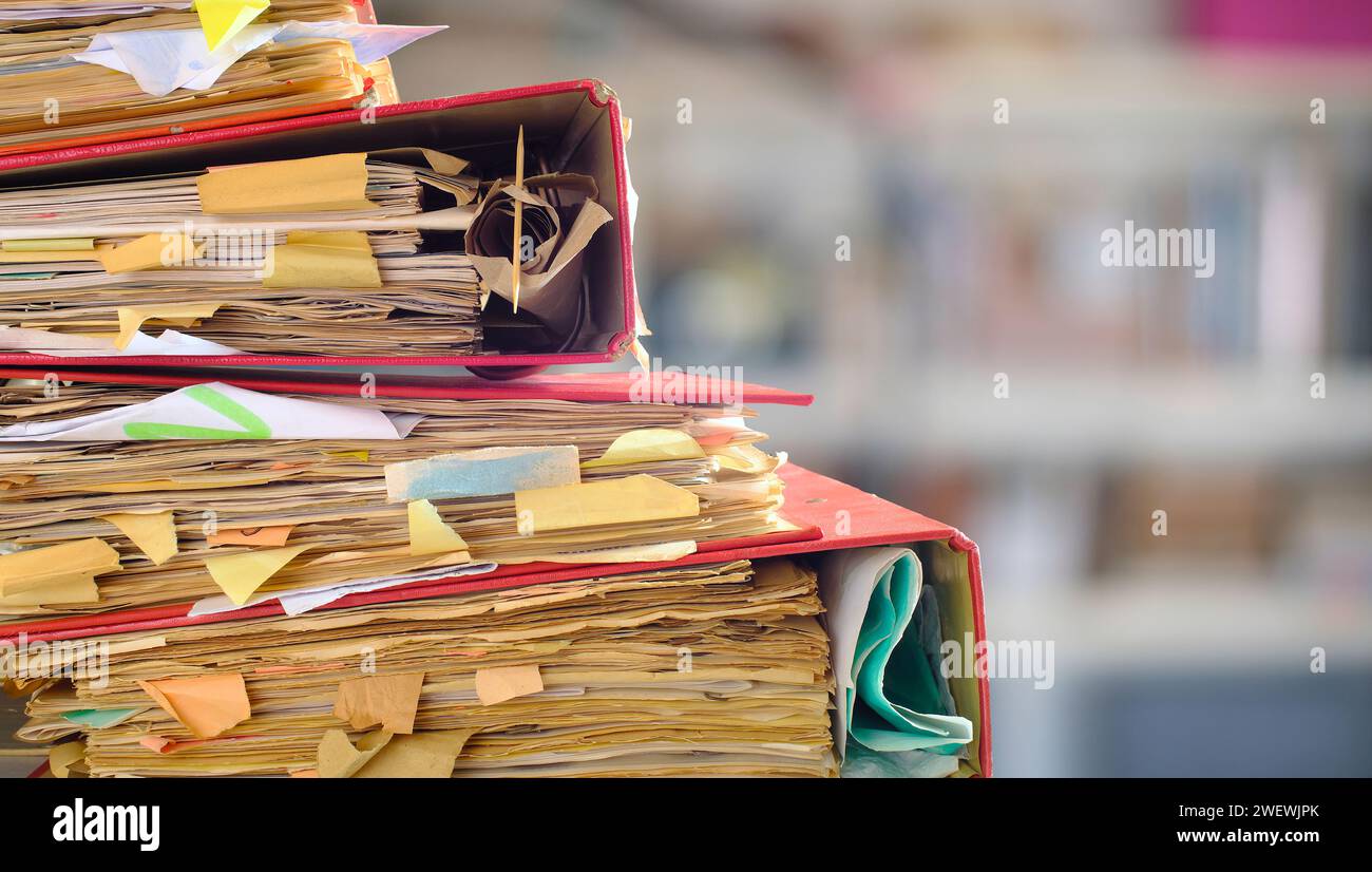 carpetas de archivos desordenados, cinta roja, burocracia, aministración, concepto de negocio, aislado en la estantería de oficina borrosa backgound Foto de stock