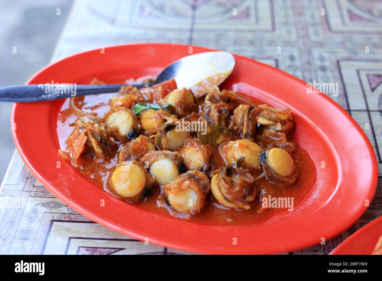 Tumis Kerang Saus Padang, Stir Fry Clams con Salsa Picante en Plato Rojo Foto de stock