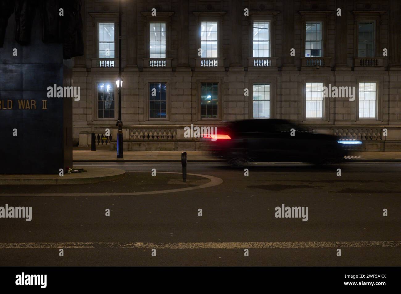 26 Ene 2024 - LondonUK: Parte del Monumento a las Mujeres de la Segunda Guerra Mundial en Whitehall en Londres por la noche con el coche que pasa en movimiento desenfoque Foto de stock