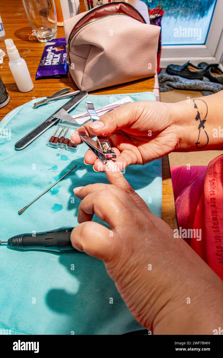 Una señora recortando sus uñas listo para aplicar nuevo barniz de uñas en casa. Foto de stock