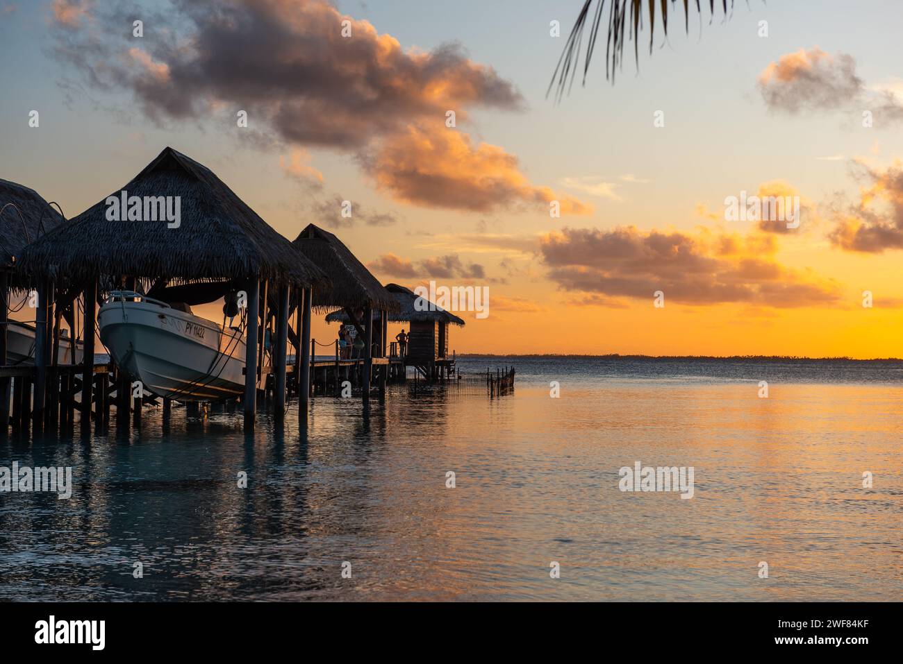 Puesta de sol sobre la laguna de Fakarava en la Polinesia Francesa, con embarcadero y elevación de barco. Foto de stock