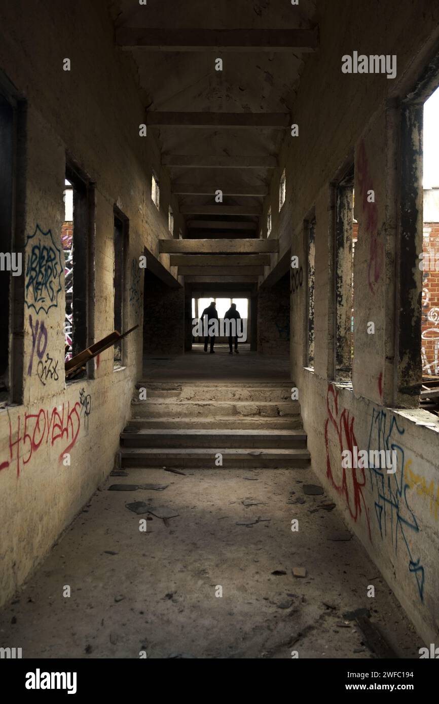 Dos personas paseando por una fábrica abandonada Foto de stock
