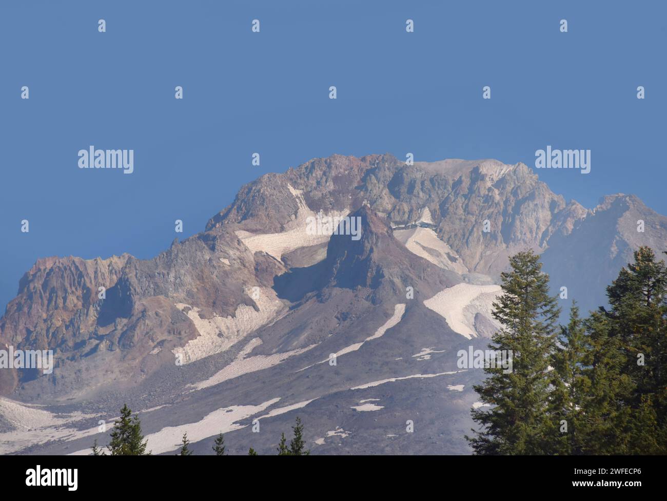 El pico escarpado del Monte Hood está enmarcado por el cielo azul. La nieve todavía se aferra a la superficie. Foto de stock