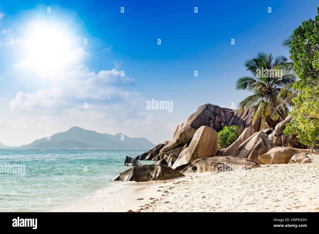 Playa de la isla tropical de arena blanca, palmeras, cielo azul, famosa fuente de anse d'argent en La Digue, islas Seychelles. Poca profundidad de campo con enfoque Foto de stock