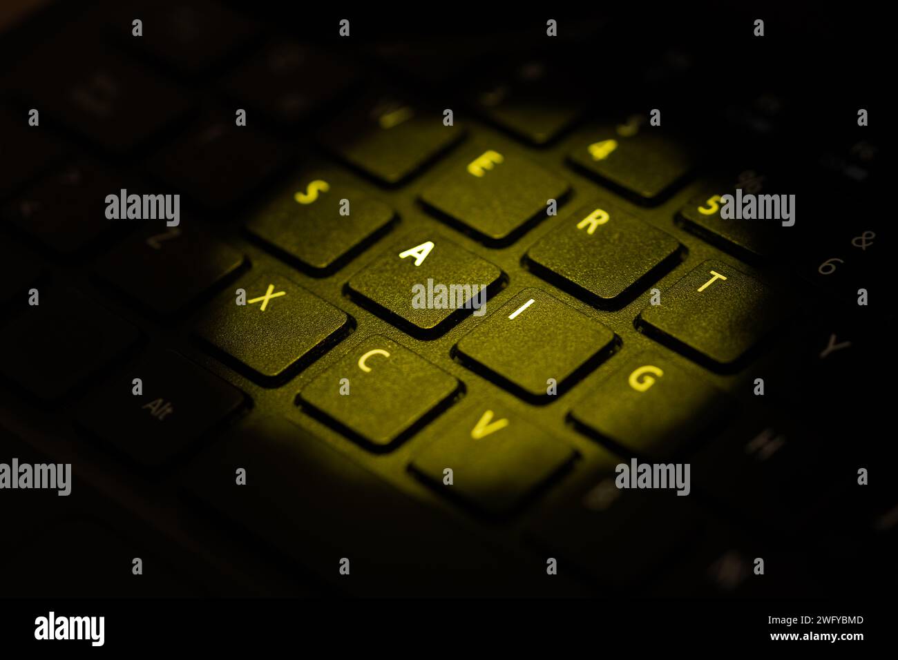 teclado iluminado con luz amarilla destacando letras a i. Foto de stock