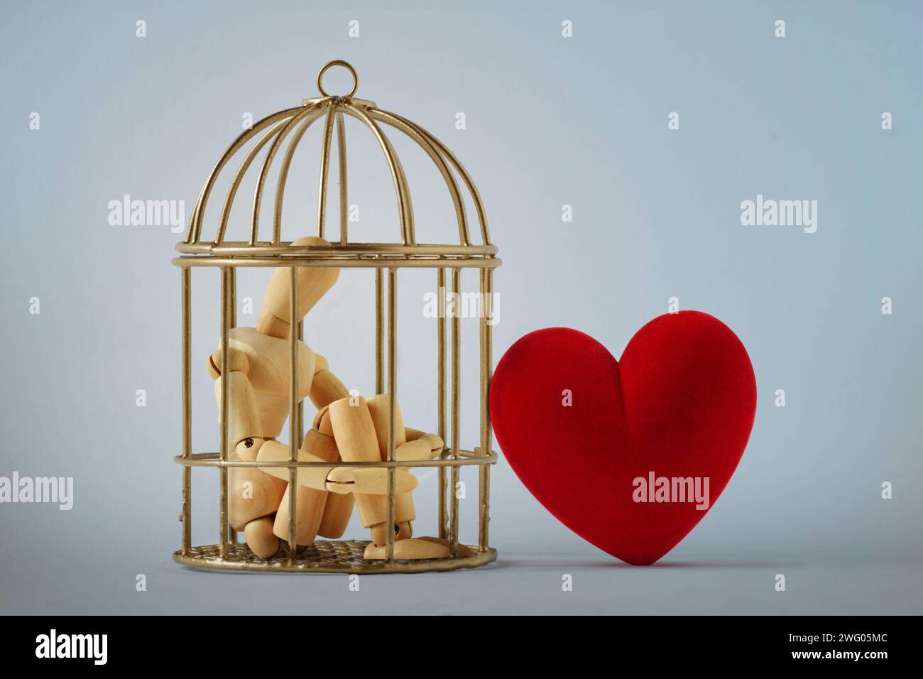 Maniquí de madera en una jaula de pájaro y corazón libre - Amor y concepto de libertad Foto de stock