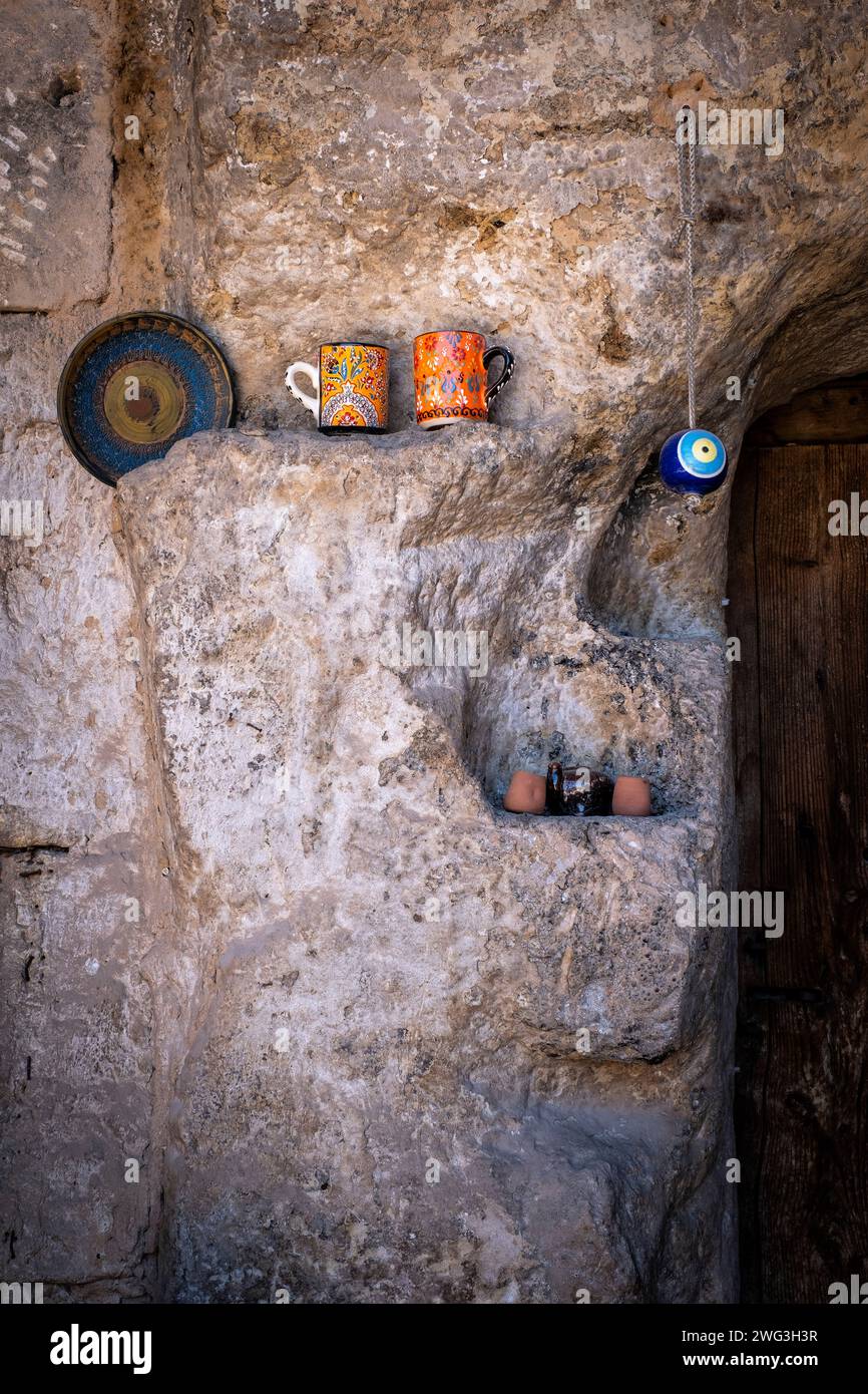 decoración en la puerta de una puerta de una casa tallada en roca en capadocia, turquía, algunas tazas, un plato y un juego de té con un amuleto típico turco Foto de stock