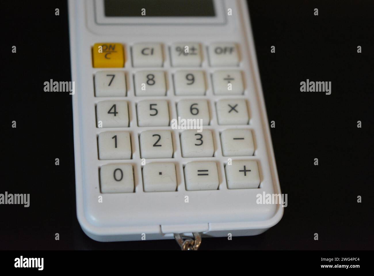 Pequeña calculadora de diseño hermoso blanco brillante que miente en una superficie brillante negra. Foto de stock