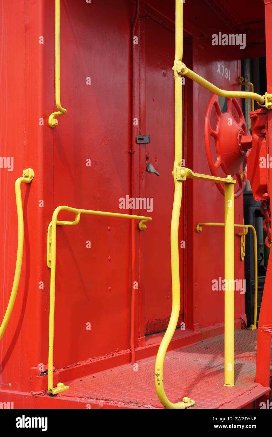 Una impactante fotografía captura el contraste entre el cuerpo rojo y los pasamanos amarillos de un vagón de ferrocarril, enfatizando sus colores llamativos Foto de stock