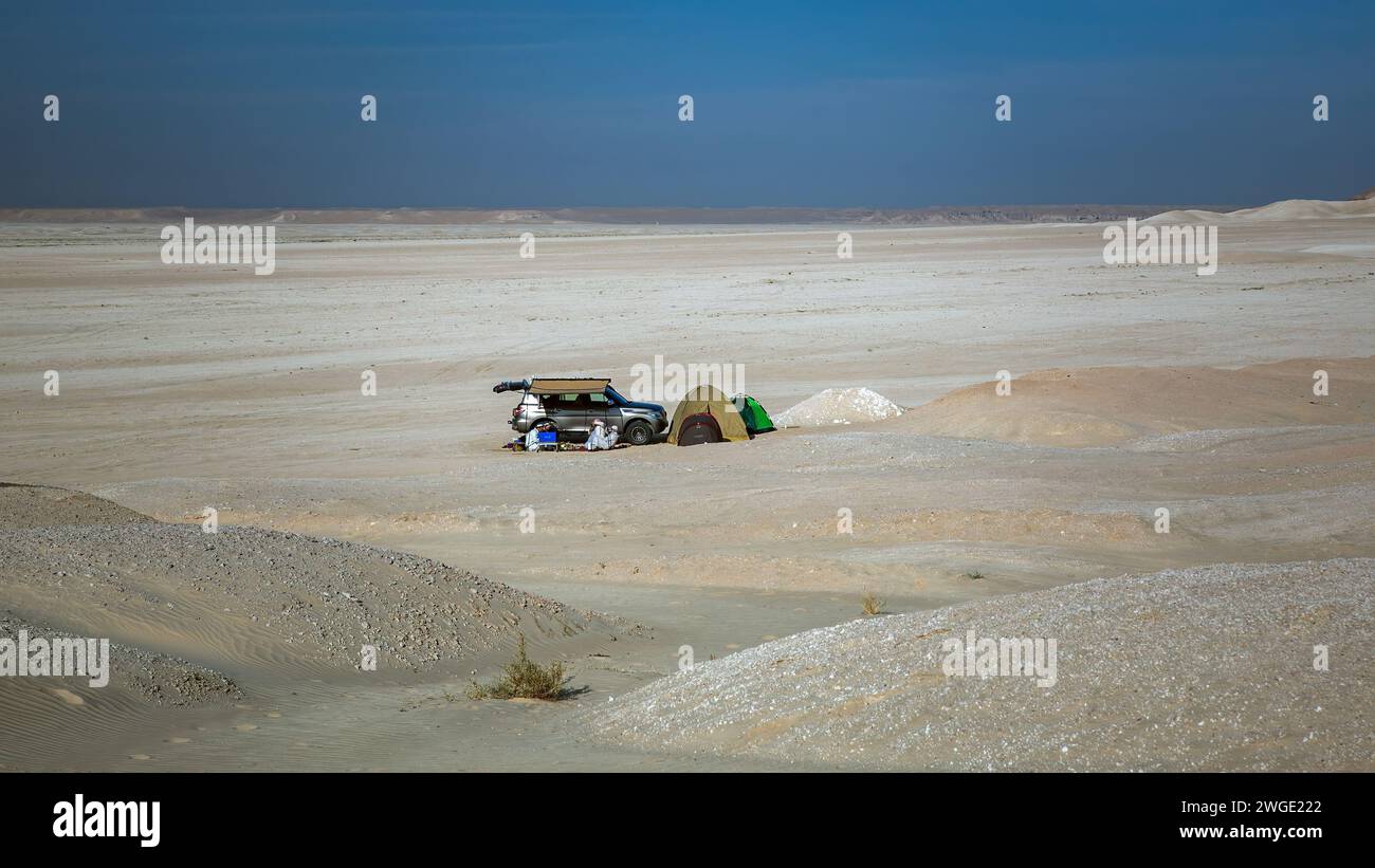 Un pequeño grupo de personas descansando en el calor en el desierto cerca de su coche, en una tienda de campaña, cerca de Dhahran, Arabia Saudita. Foto de stock