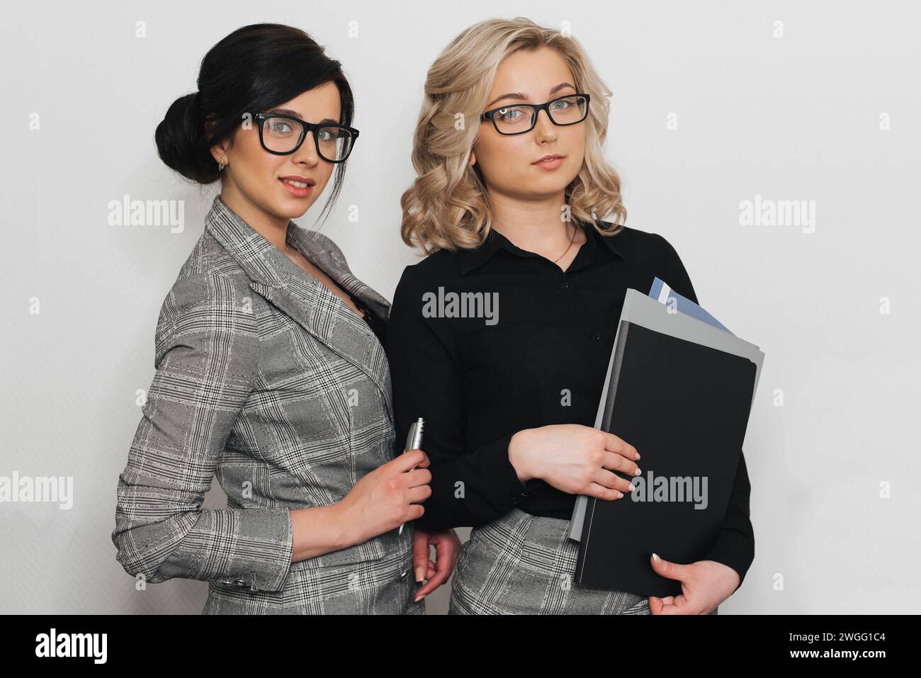 Dos atractivas secretarias con gafas con documentos de apariencia caucásica Foto de stock