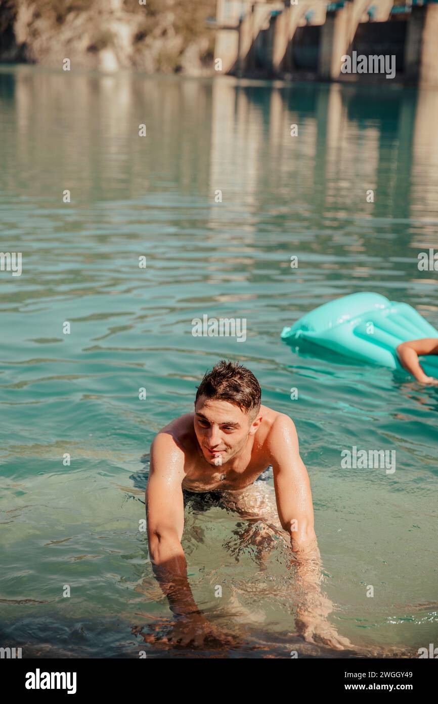 Joven bañándose en el lago turquesa durante el día soleado de verano Foto de stock