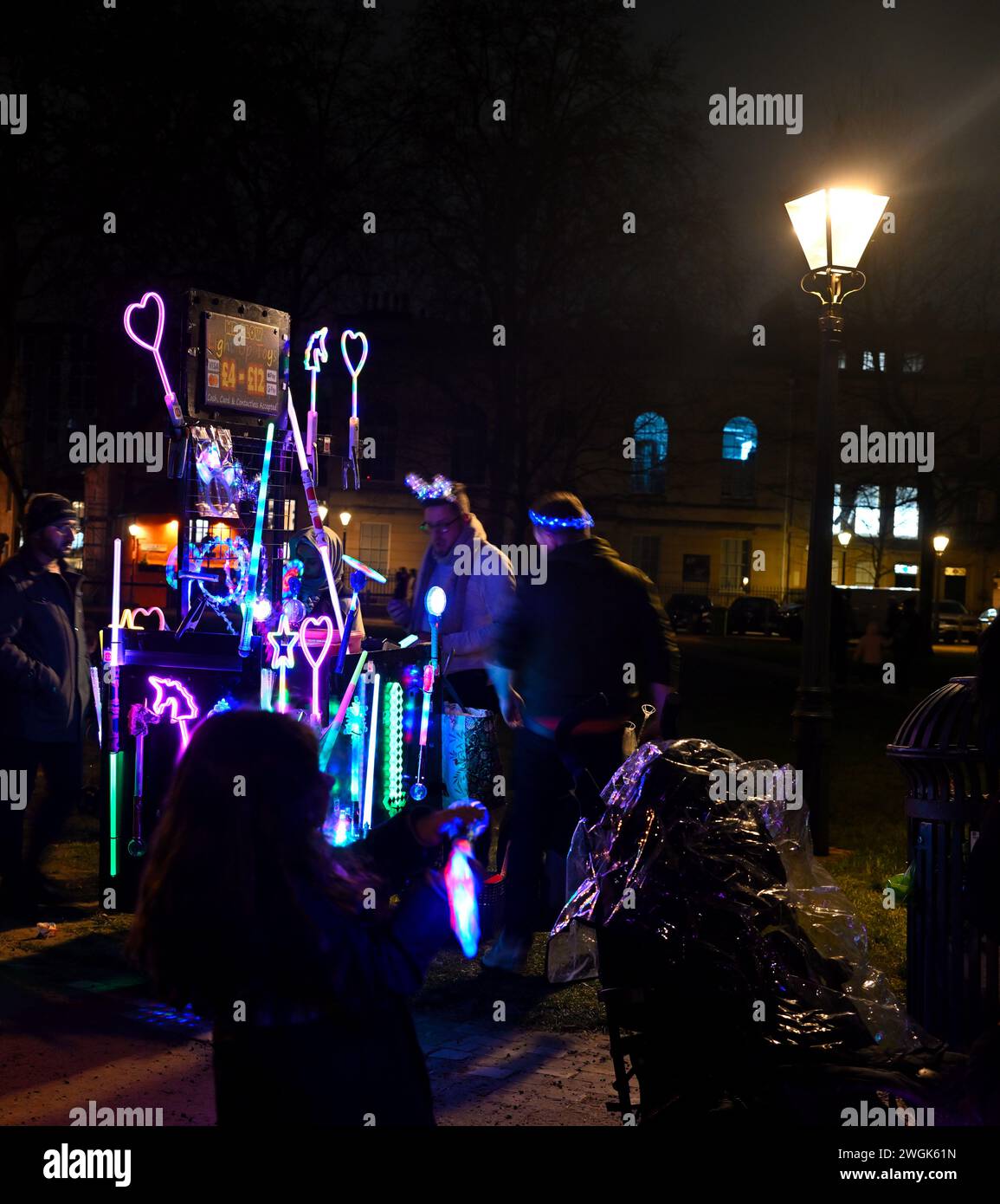 Vendedor callejero nocturno que vende variedad de palos de luz led Foto de stock
