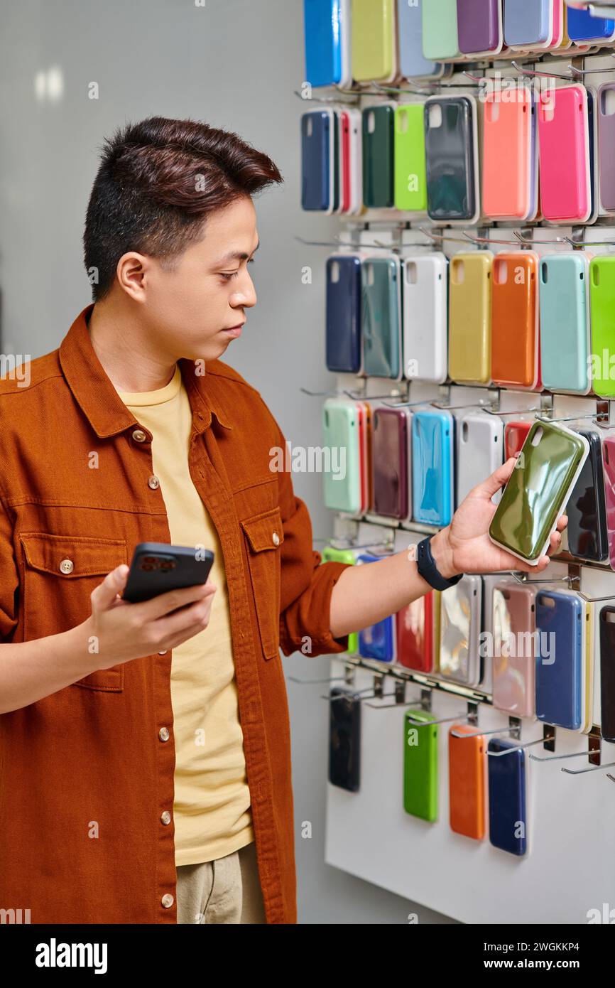 propietario asiático de la tienda con el teléfono inteligente mirando la caja del teléfono en el punto privado de la tienda, pequeña empresa Foto de stock