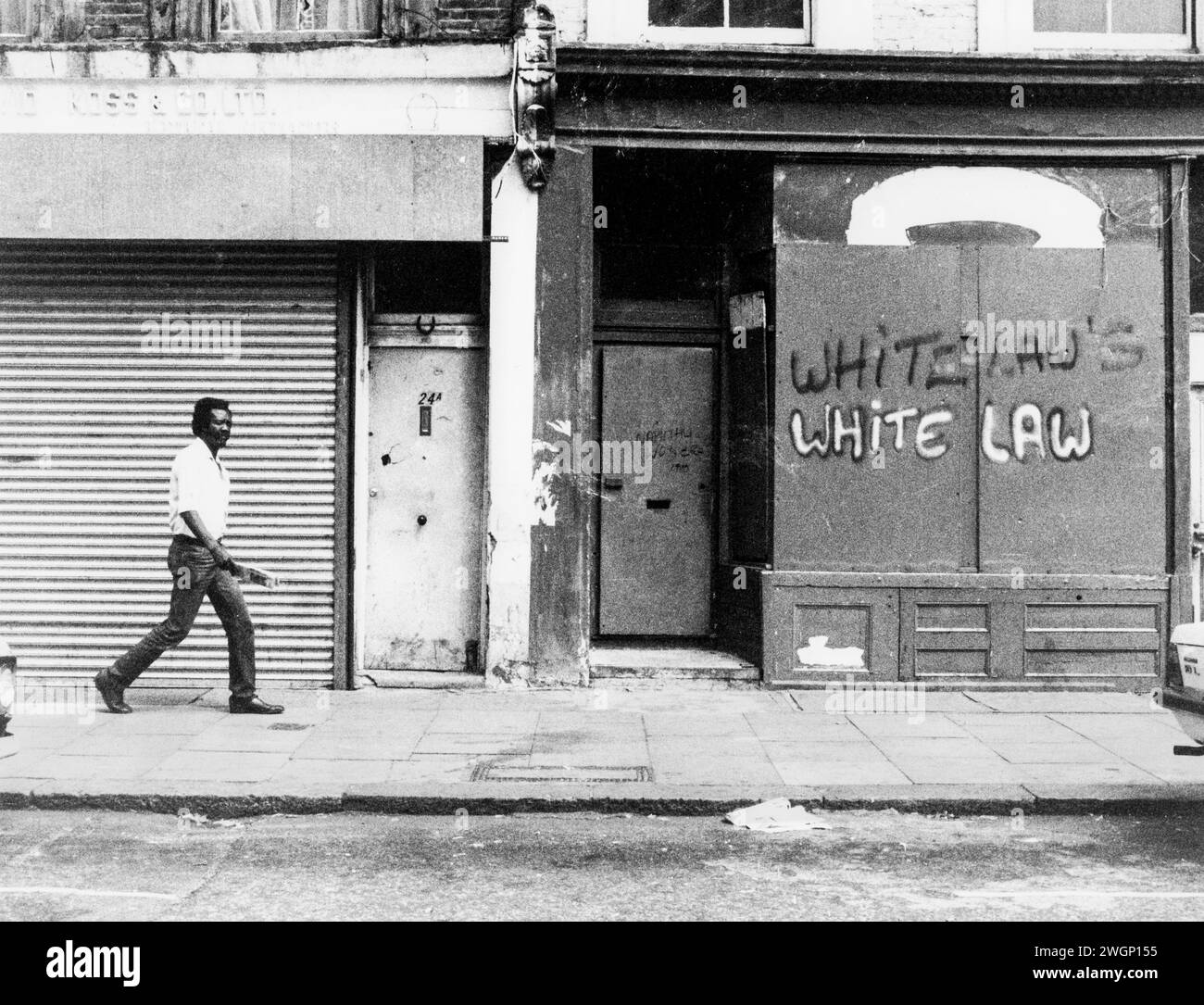 Graffiti en frente de una tienda, 22 All Saints Road cerca del restaurante Mangrove, Notting Hill, Londres, 1971. El restaurante fue inaugurado en 1968 por el activista de derechos civiles Frank Crichlow y fue un lugar de reunión para la comunidad negra local. Con frecuencia allanada por la policía que llevó a protestas y a un famoso juicio en 1971. El juicio de los Nueve Manglar llamó la atención pública sobre el racismo policial, y convirtió la lucha contra él en una causa célèbre. El graffiti 'Whitelaws - White Law' alude al secretario conservador del Interior William Whitelaw y la posición del gobierno conservador con respecto a la policía y el racismo. Foto de stock