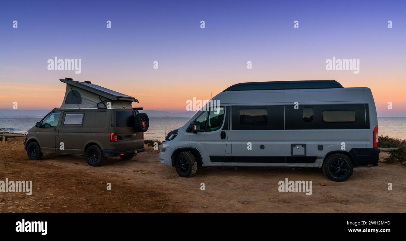 Santa Pola, España - 4 de febrero de 2024: Dos autocaravanas estacionadas en un estacionamiento de arena junto a la playa al atardecer Foto de stock