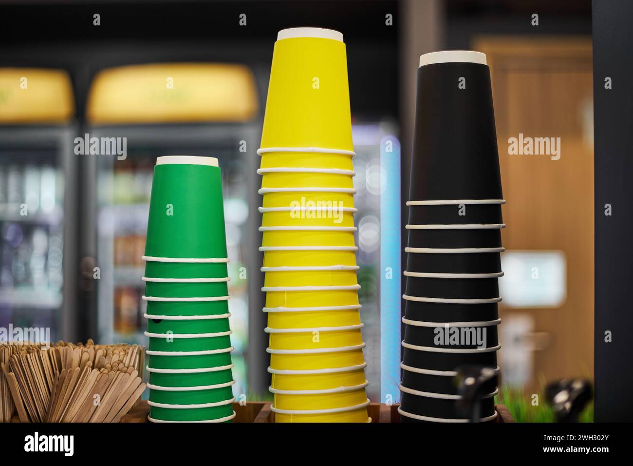 En blanco tres pilas de tazas de papel de colores, verde amarillo negro taza diferentes tamaños para bebidas calientes café, té para llevar. Maqueta para cafetería, stor Foto de stock