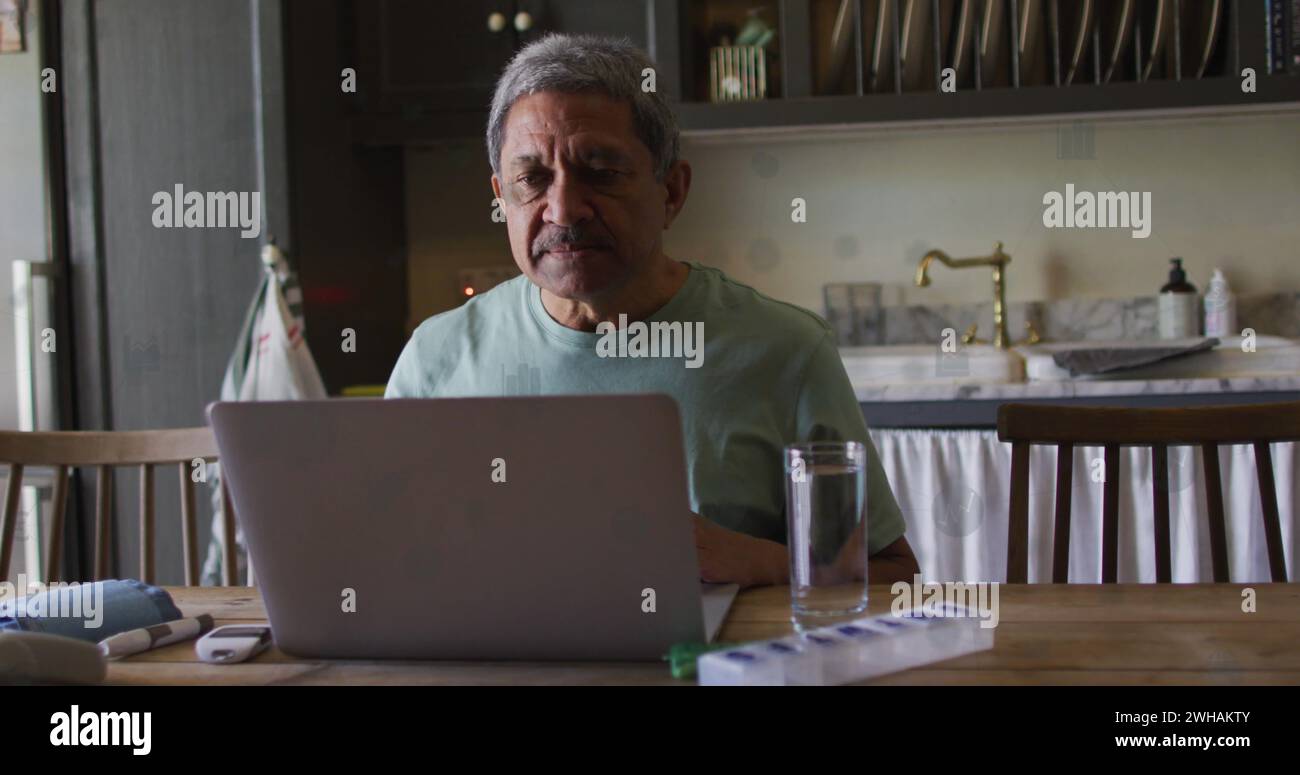 El hombre biracial mayor trabaja en una computadora portátil en casa Foto de stock